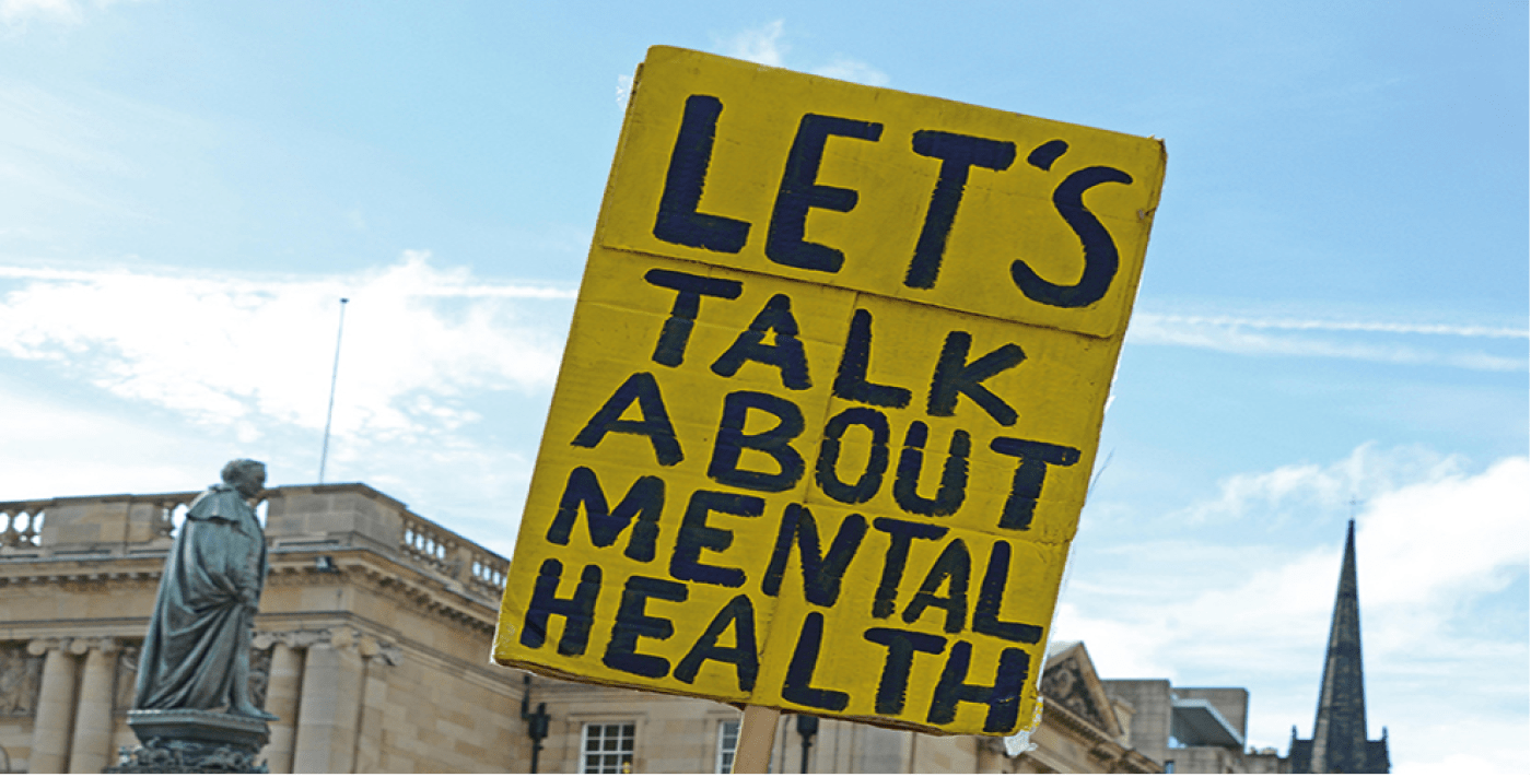 a sign at a protest which says "Lets talk about mental health"