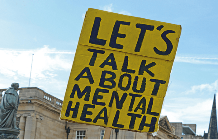 a sign at a protest which says "Lets talk about mental health"